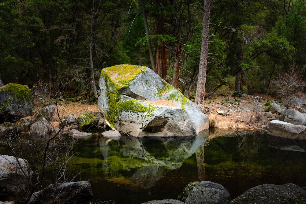 Large boulder at edge of pool and reflected in water