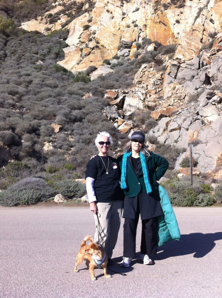 Claudia, her mother, and dog Keira standing in front of a rocky cliff