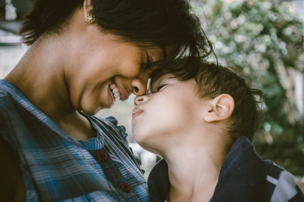 Photo of mother and young son with faces touching each other